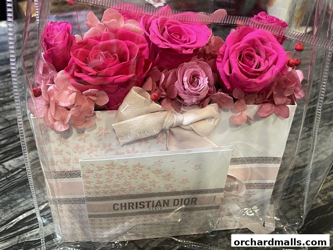 A beautifully arranged bouquet of pink roses and hydrangeas in a Dior branded box.