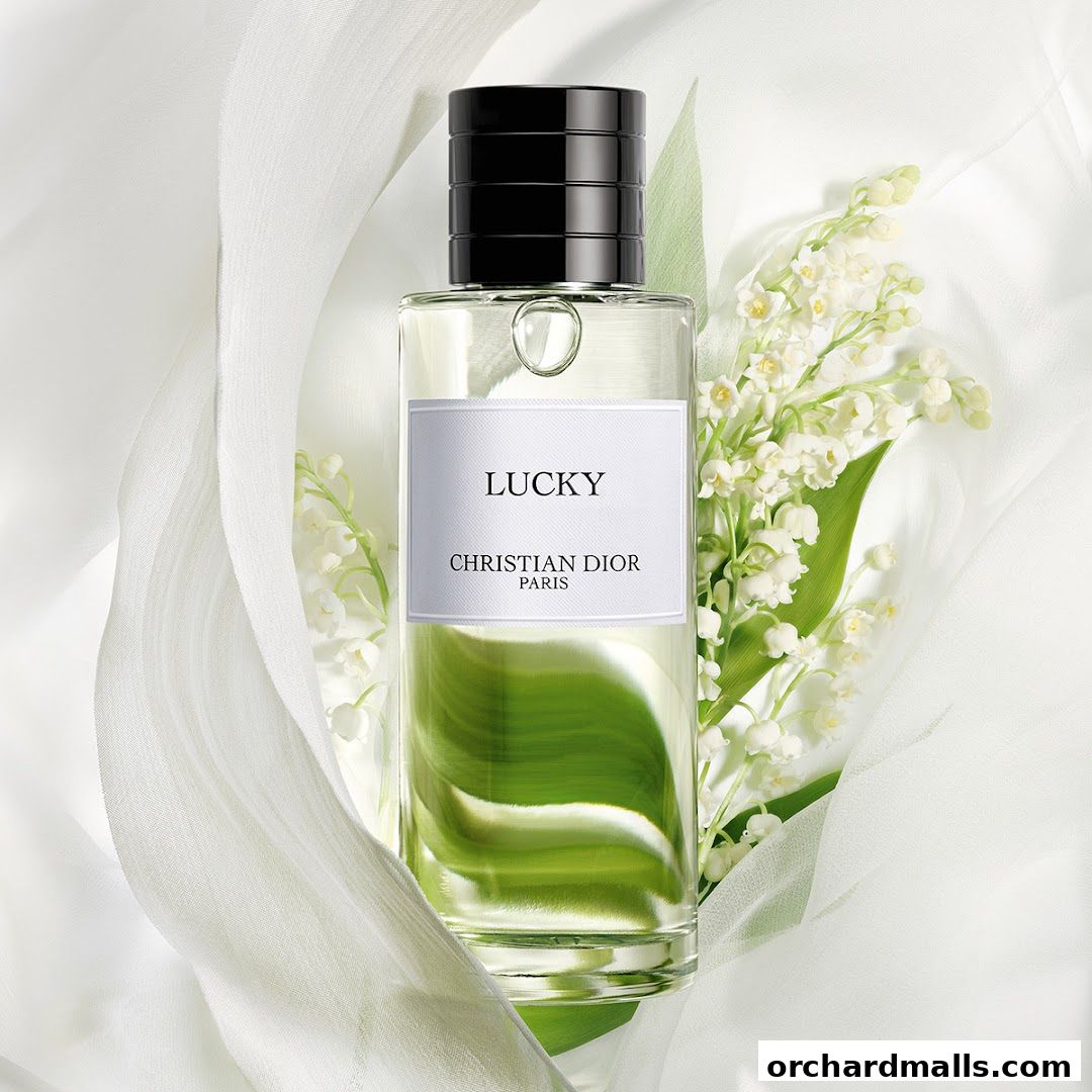 A bottle of Dior 'Lucky' perfume with lily of the valley flowers and white fabric.