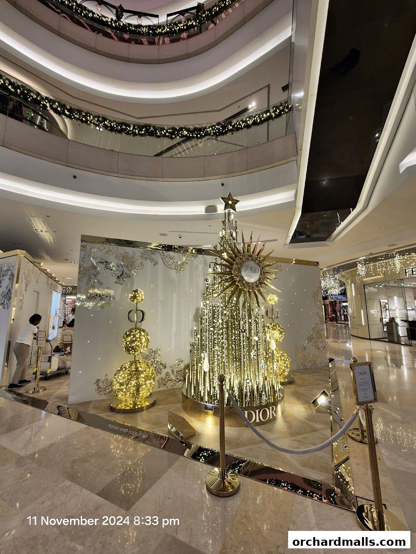 A festive Dior display with a sparkling Christmas tree and golden ornaments in a mall.