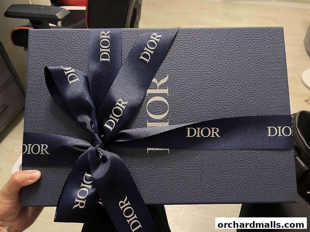 A textured blue Dior gift box tied with a navy ribbon featuring the Dior logo.
