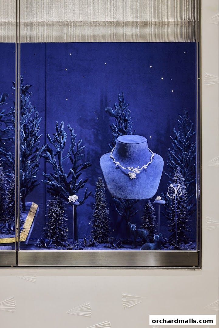 Dior window display featuring a necklace on a bust amidst a winter forest scene.