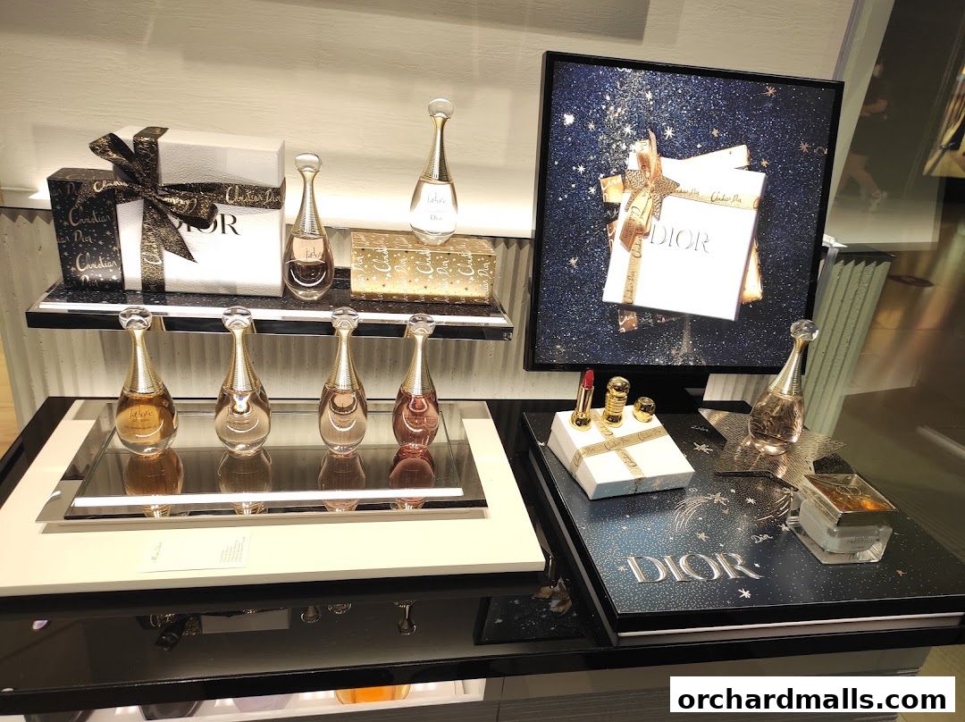 Dior J'adore perfumes and makeup displayed with festive packaging and a digital screen.