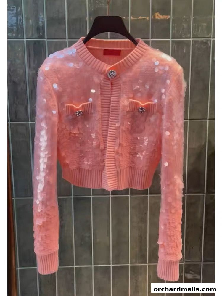 A pink sequined cardigan with button closure and decorative pockets.