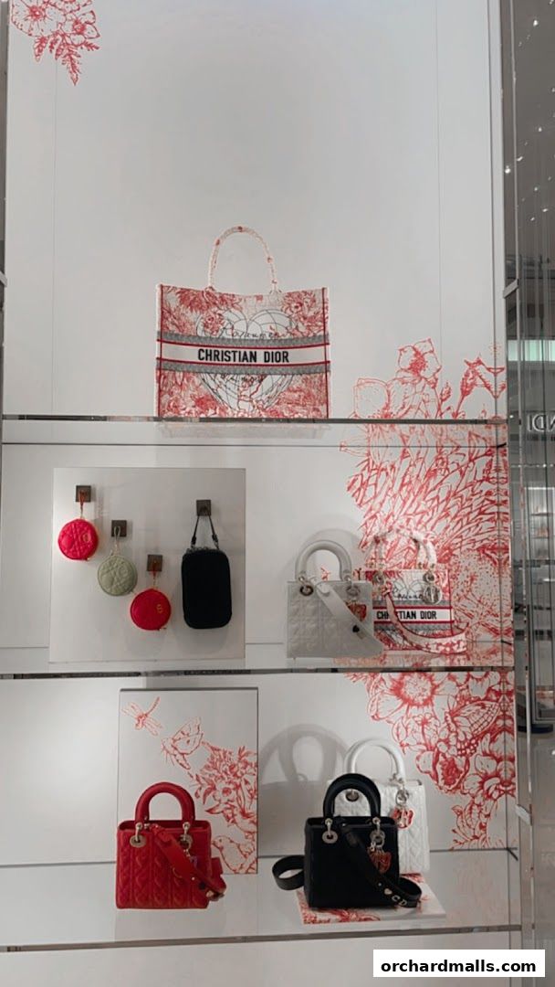 Dior handbags displayed in a store window with floral and nature-inspired motifs.