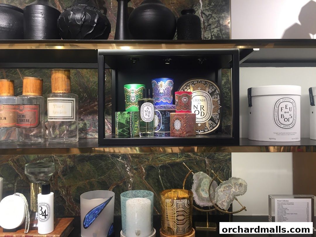 A display of Diptyque candles, perfumes, and home fragrances on shelves.