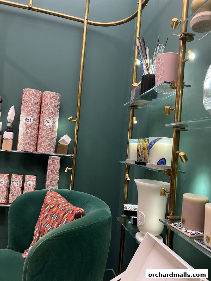 Interior of a Diptyque shop featuring candles, diffusers, and a plush green armchair.