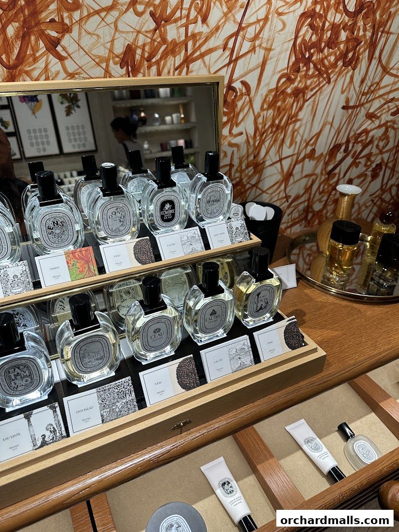 A display of Diptyque perfumes and hand creams in a well-lit retail setting.