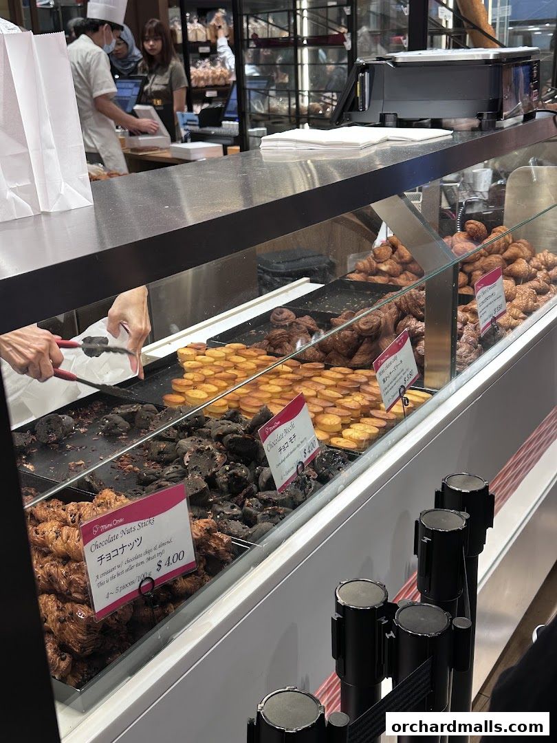 A display case filled with various pastries, including croissants and cookies, at a bakery.
