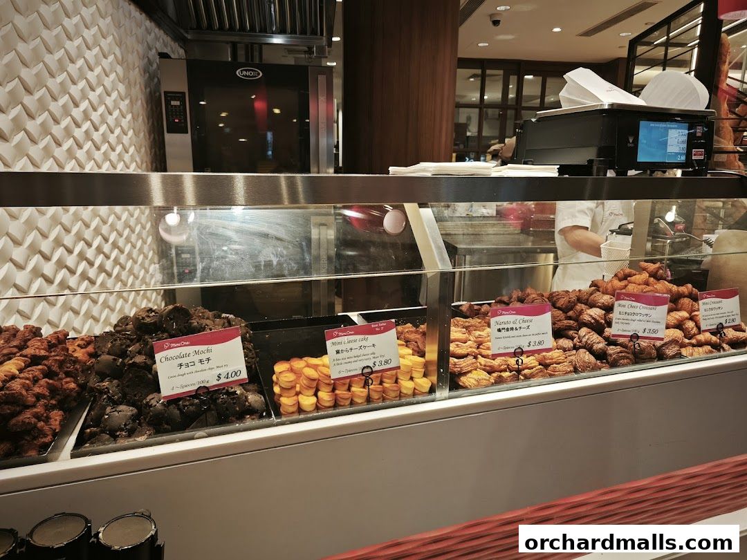 A display case filled with various pastries, including croissants and mochi, at a bakery.