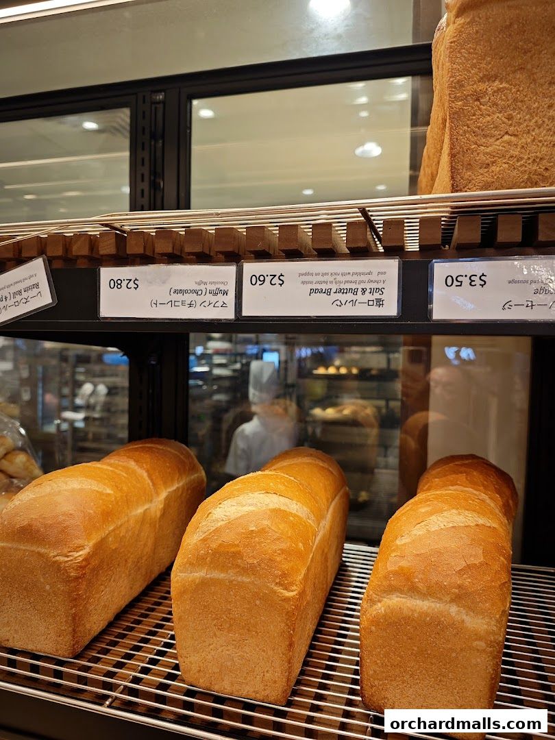 Freshly baked loaves of bread displayed on a shelf with price tags.
