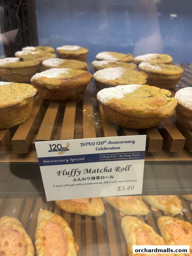 A display of fluffy matcha rolls dusted with powdered sugar at a bakery.