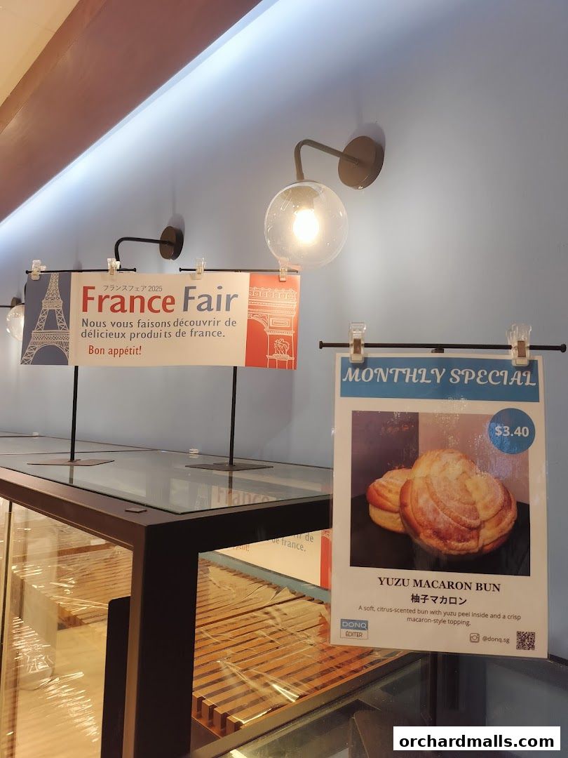 A bakery display case with signs for a France Fair and a monthly special Yuzu Macaron Bun.