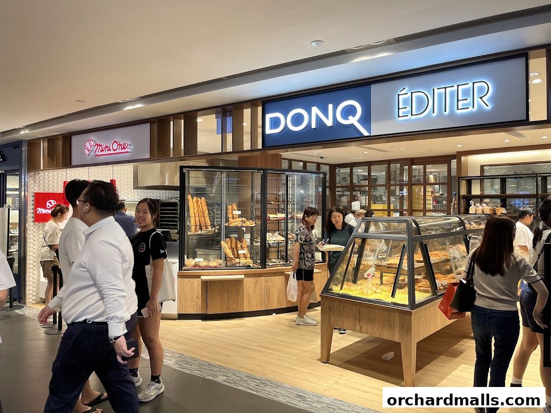People are browsing at a bakery with display cases filled with bread and pastries.