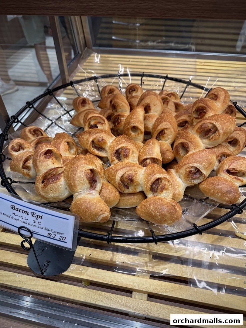 A basket of freshly baked Bacon Epi bread rolls with a price tag.