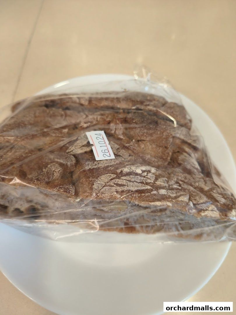 A close-up shot of a loaf of bread packaged in plastic on a white plate.