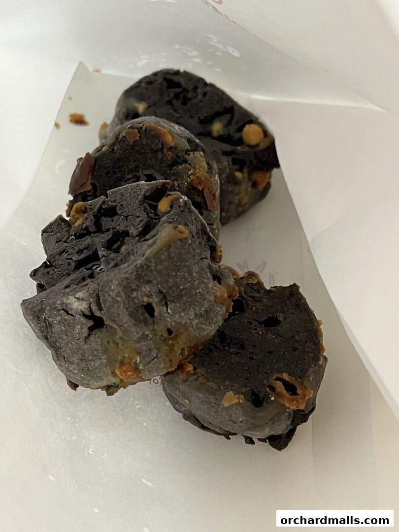 Close-up of dark, crumbly baked goods with visible nuts inside a paper bag.
