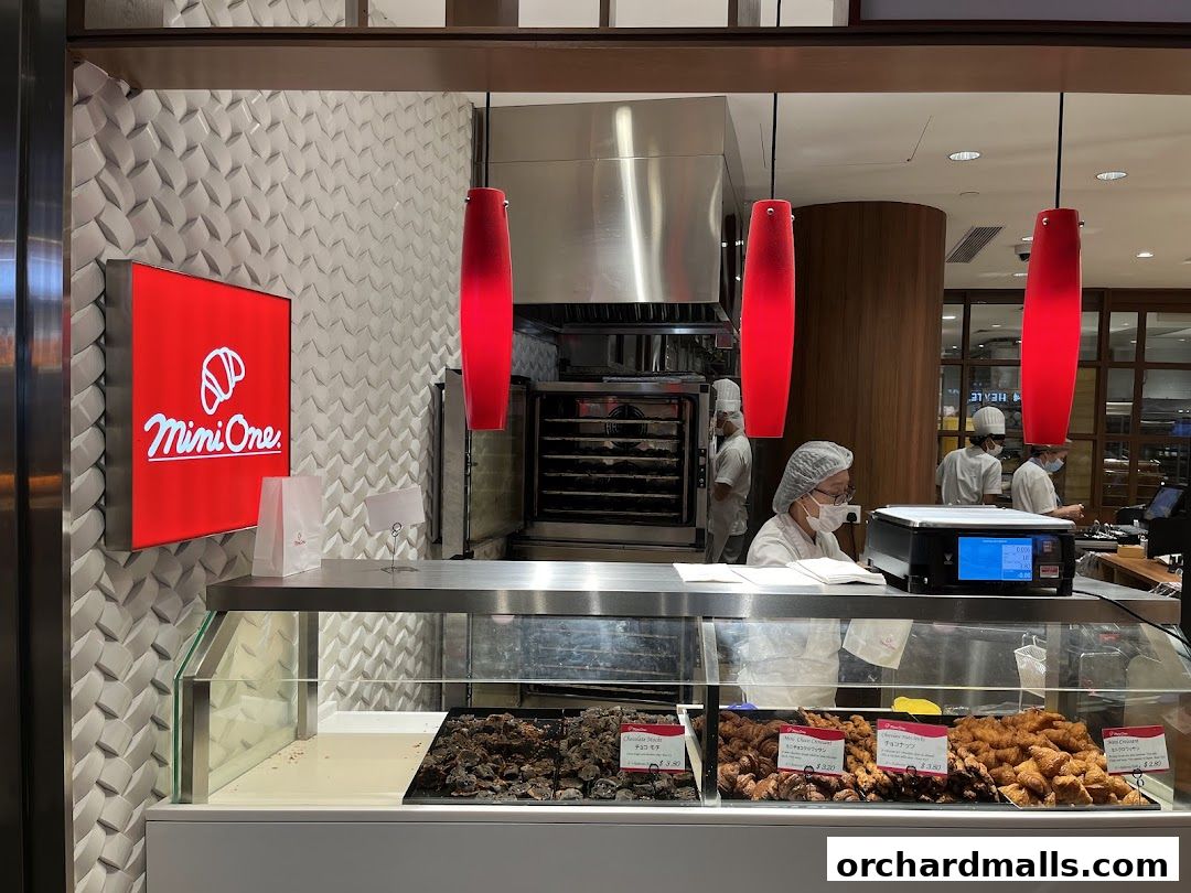 A bakery counter with various pastries and staff members working behind it.