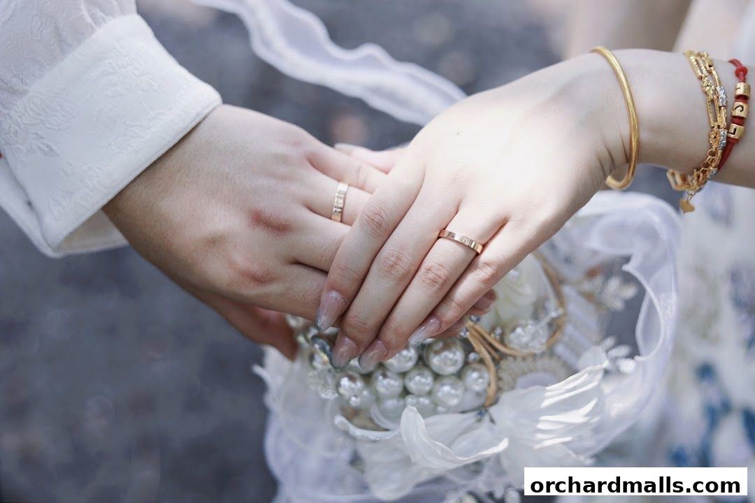 Close-up of two hands wearing wedding rings, holding a bouquet.