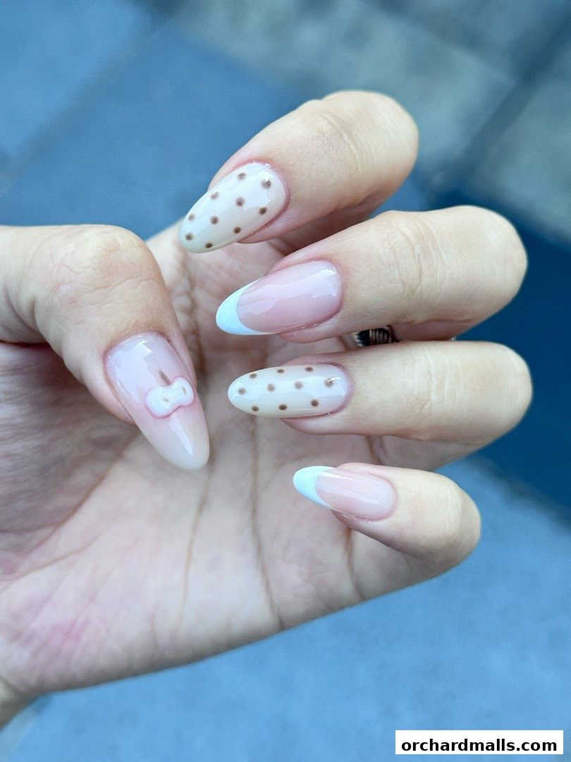 Close-up of a hand with beautifully designed nails featuring polka dots and French tips.