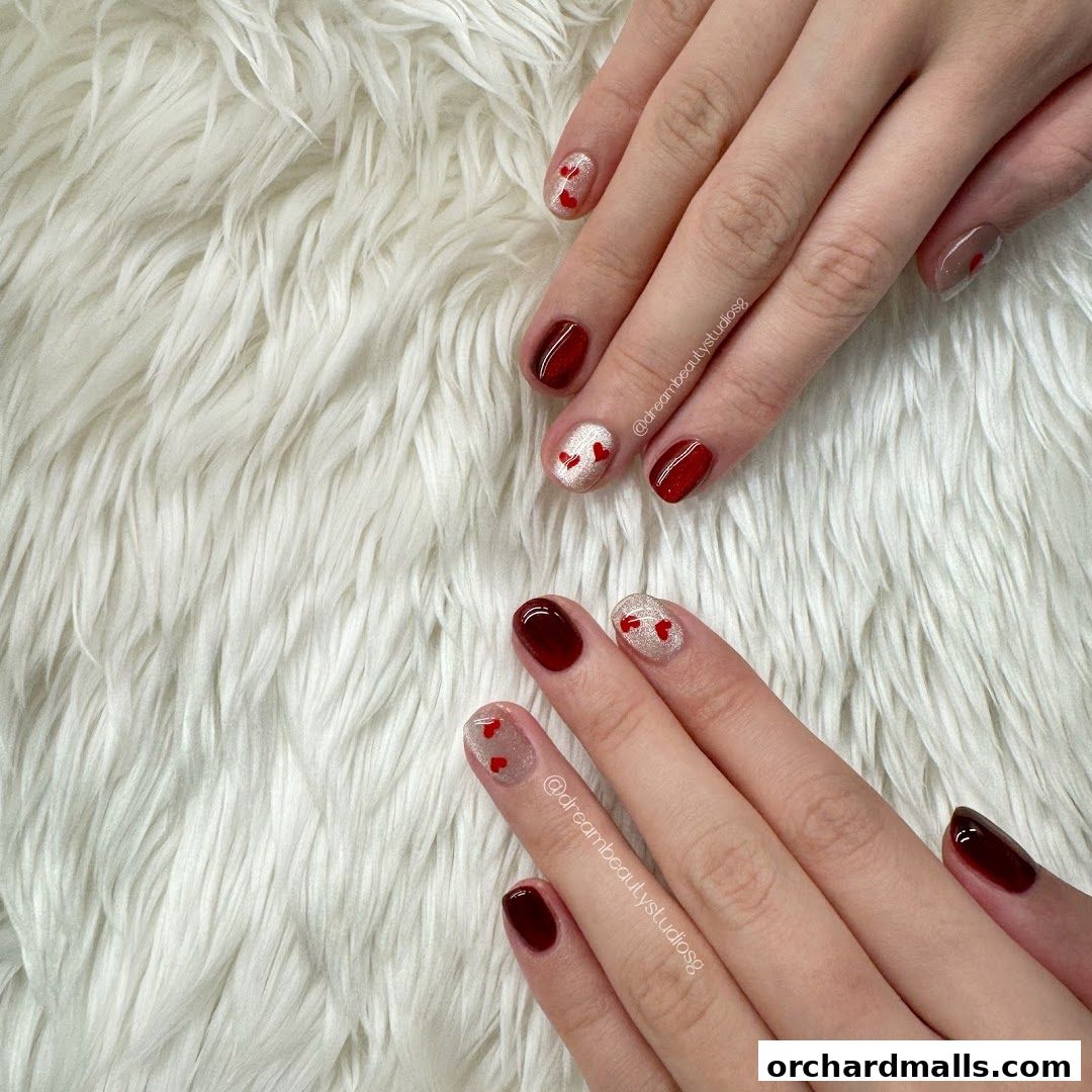 Close-up of hands with beautifully manicured nails featuring red and glitter designs.