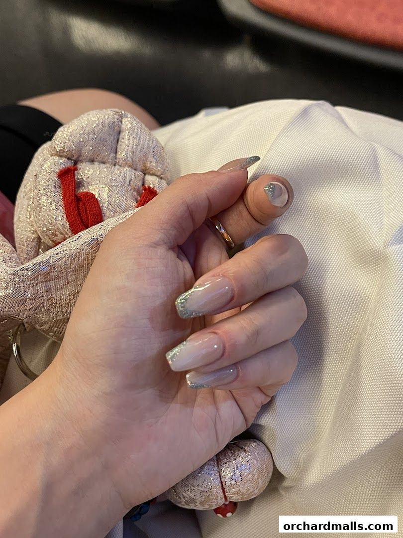 Close-up of a hand with elegant, long nails featuring a French tip with glitter.