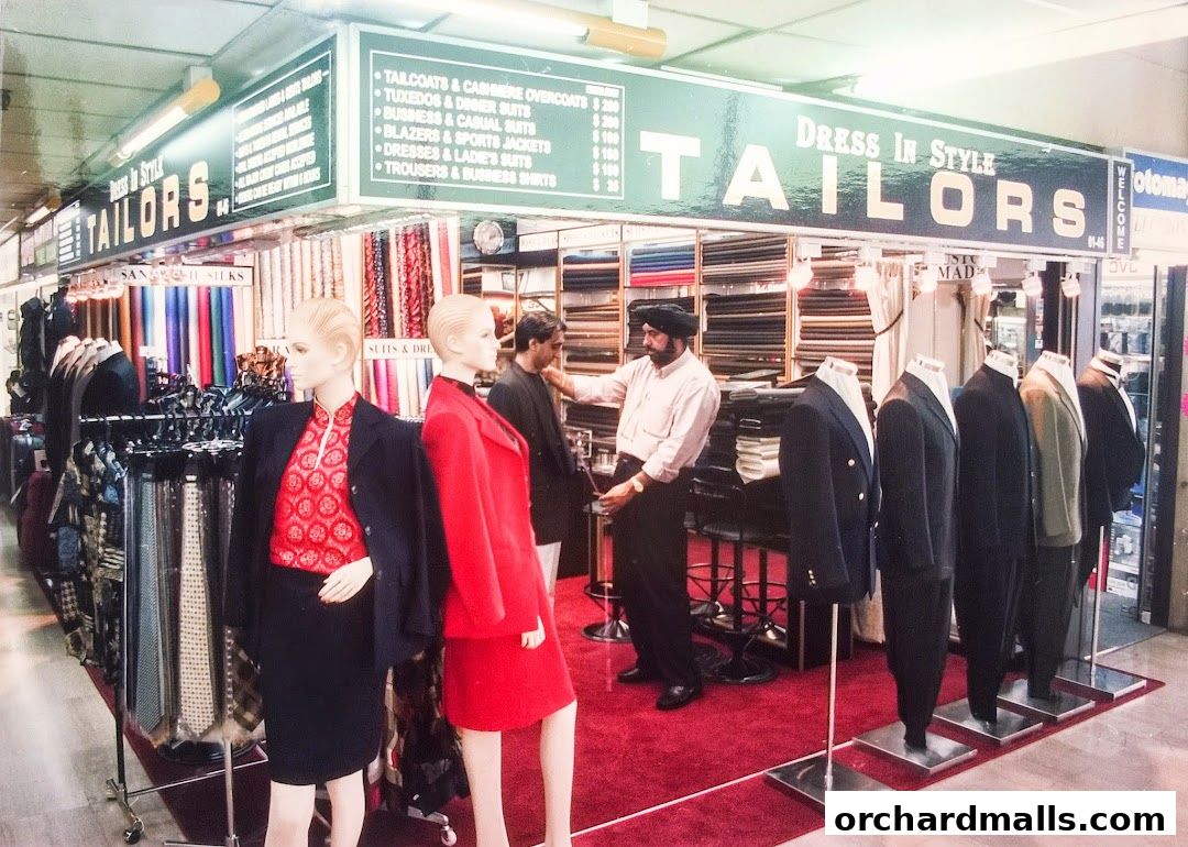 A tailor shop interior with mannequins, fabric rolls, and a tailor assisting a customer.