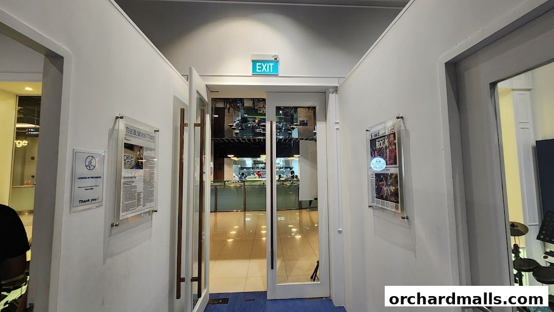 Entrance to a drum lesson studio with posters and an exit sign.