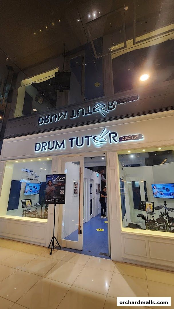 The entrance of Drum Tutor Concept, a music school with drum sets visible inside.