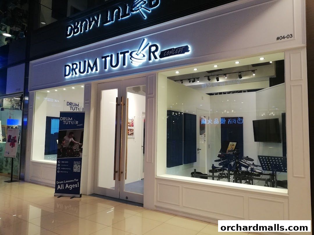 Exterior of a drum tutoring shop with a prominent sign and display of drum equipment.