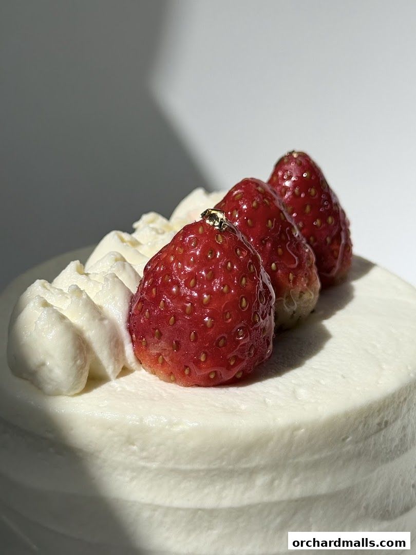 A close-up of a white cake topped with whipped cream and fresh strawberries.