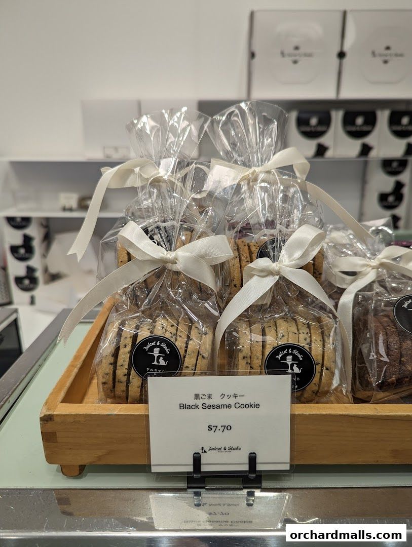 Packaged black sesame cookies displayed on a wooden tray with a price tag.