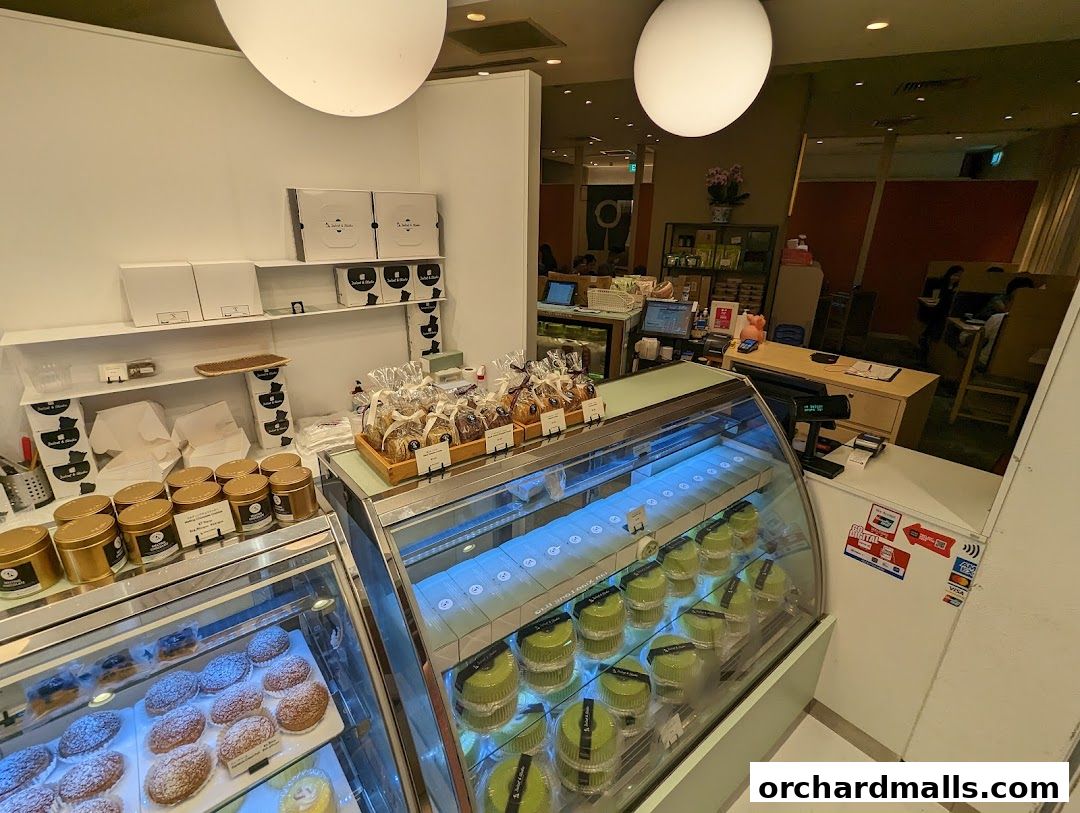 A display of pastries and cakes in a modern bakery shop with a counter in the background.