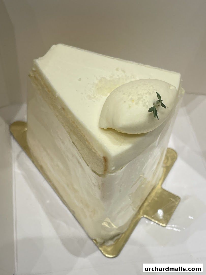A slice of white cake with cream frosting and a small garnish on top.