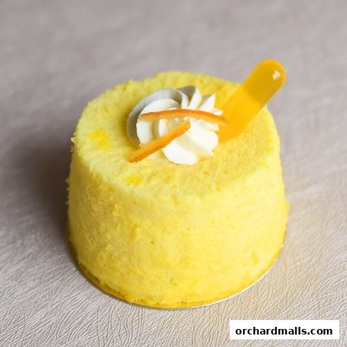 A bright yellow cake with white frosting, orange zest, and a yellow garnish.