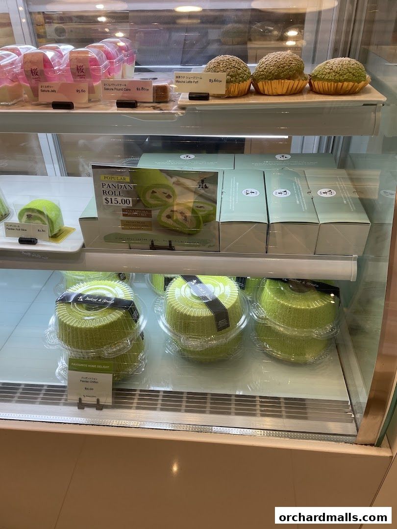 A display case filled with various pastries and cakes, including rolls and choux puffs.