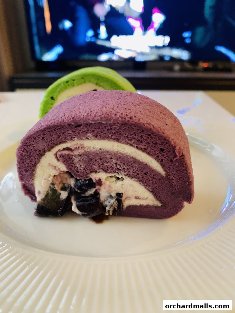 Close-up of two colorful Swiss roll cakes on a white plate.