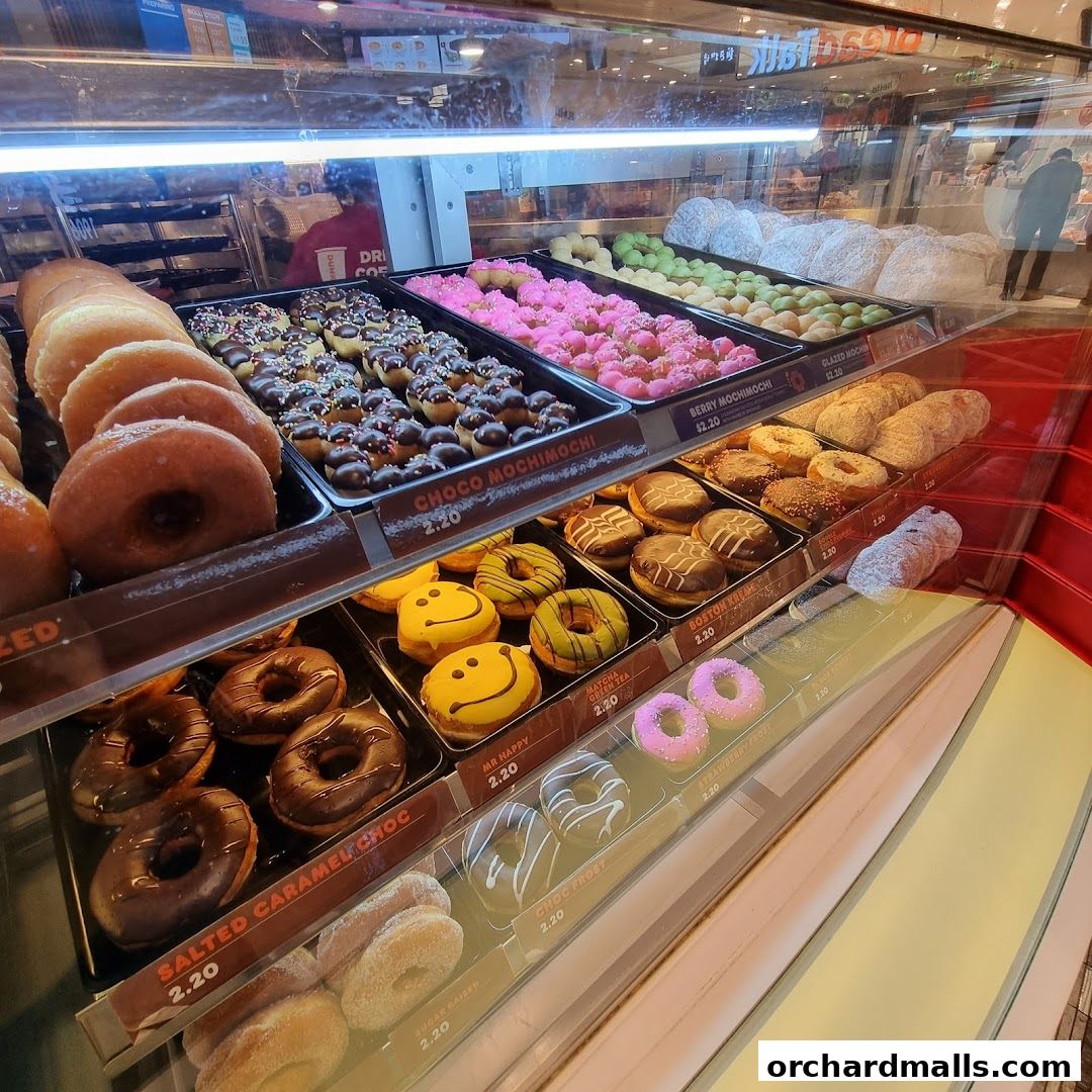 A display case filled with a variety of colorful and delicious donuts and mochi.