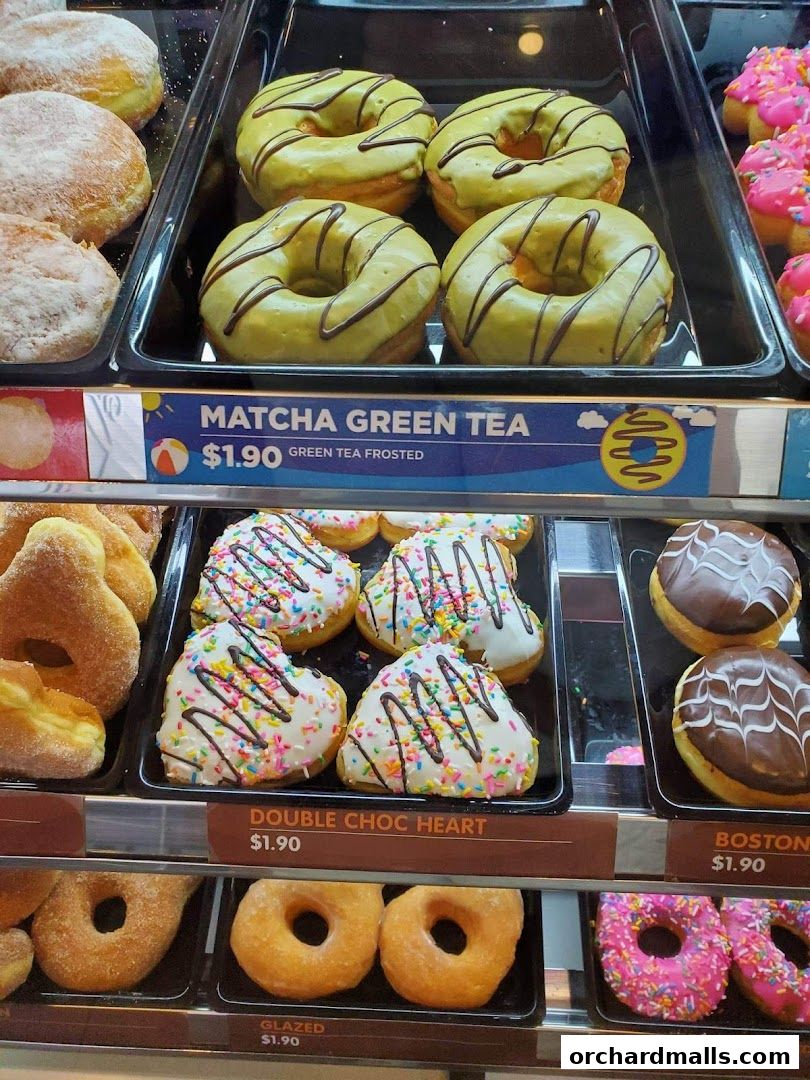 A display case filled with various colorful and frosted donuts.
