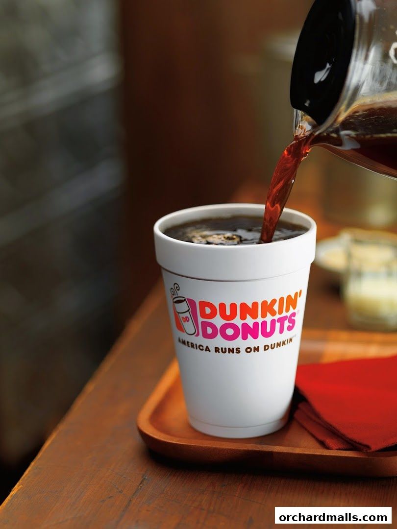 Freshly brewed coffee being poured into a Dunkin' Donuts branded cup.