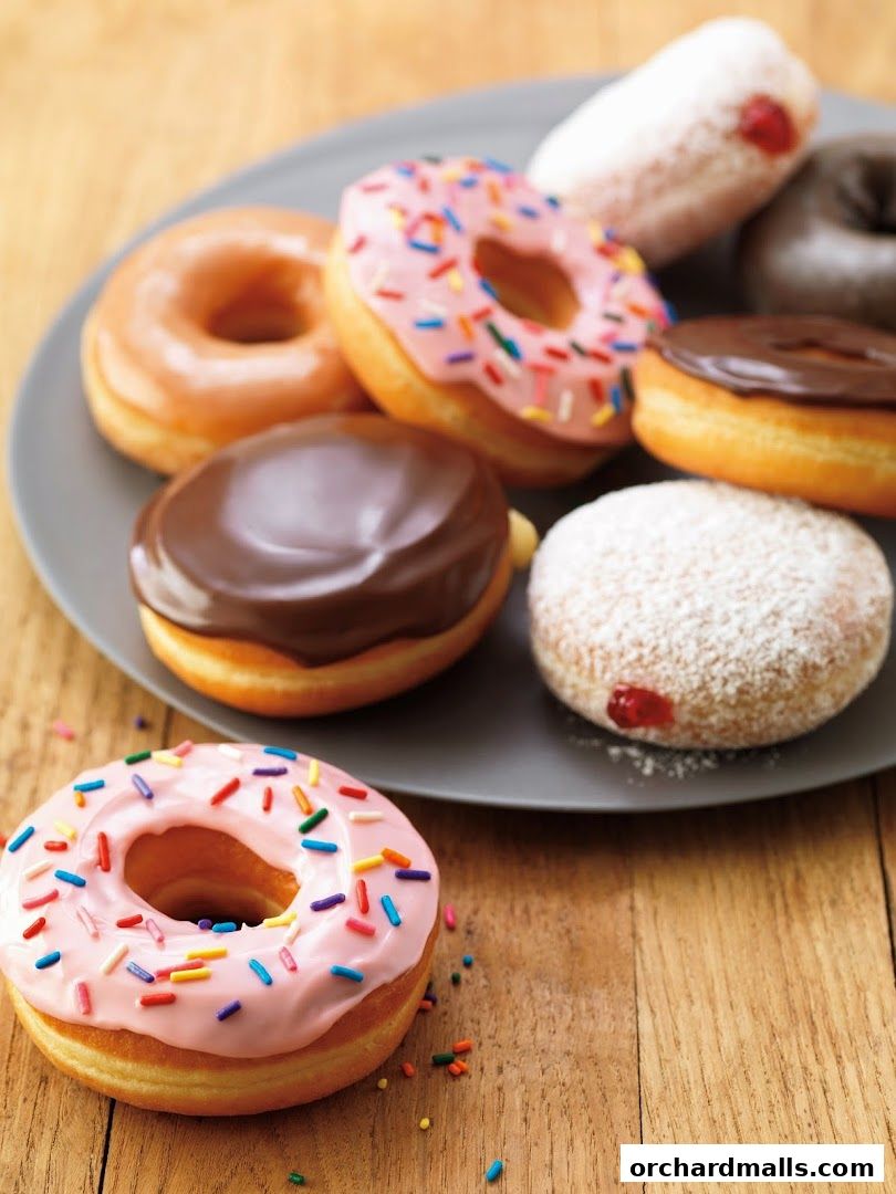 A close-up shot of various delicious donuts on a grey plate and wooden surface.