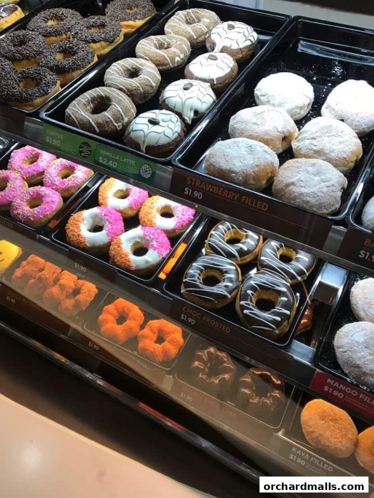 A display case filled with a variety of colorful and frosted donuts.