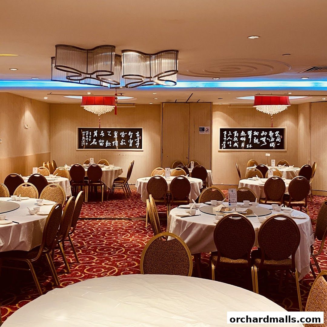 Elegant dining room with round tables set for a meal, featuring ornate chandeliers and wall art.