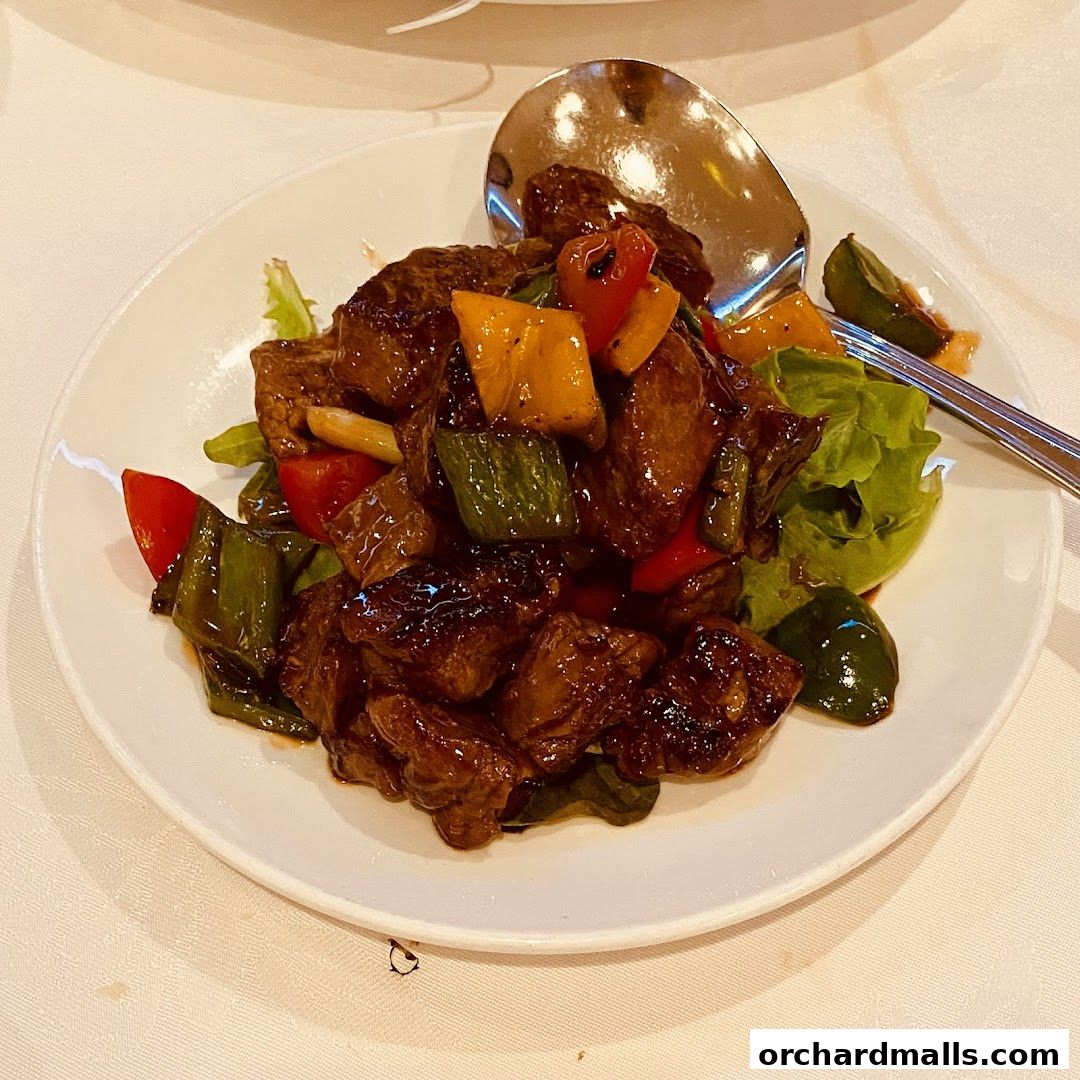 A plate of stir-fried beef with colorful bell peppers and lettuce, served with a spoon.