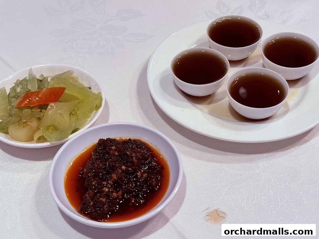 Four cups of tea and two small dishes of appetizers on a white tablecloth.
