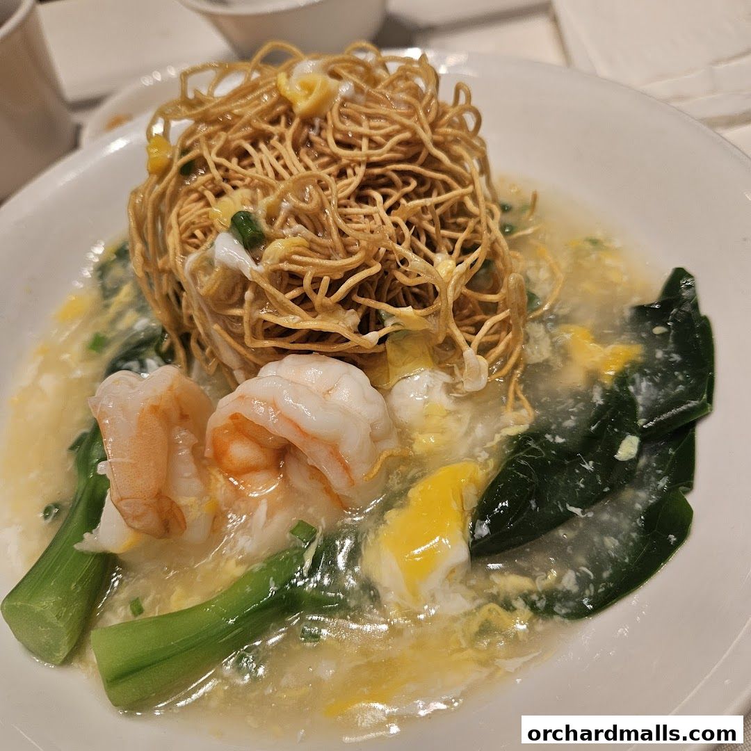 A close-up of a crispy noodle dish with shrimp and vegetables in a savory sauce.