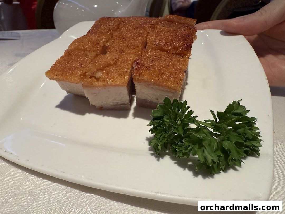 A plate of crispy roasted pork belly with a garnish of parsley.