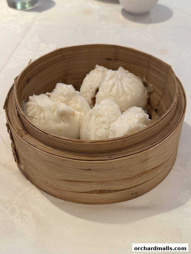 A bamboo steamer filled with delicious steamed buns on a white tablecloth.