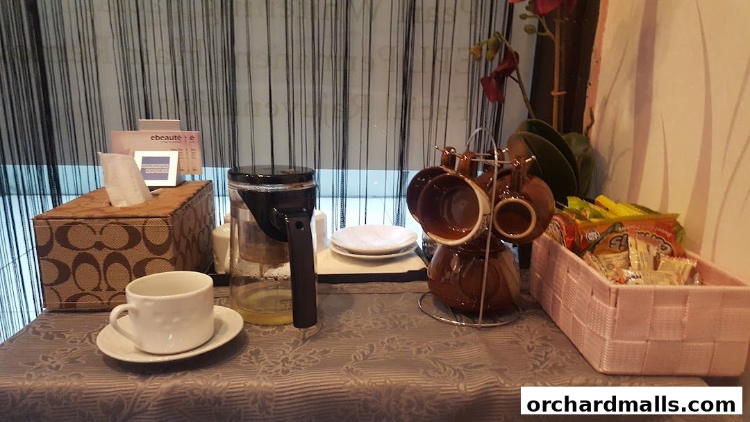 A coffee station with cups, coffee pot, snacks, and tissues.