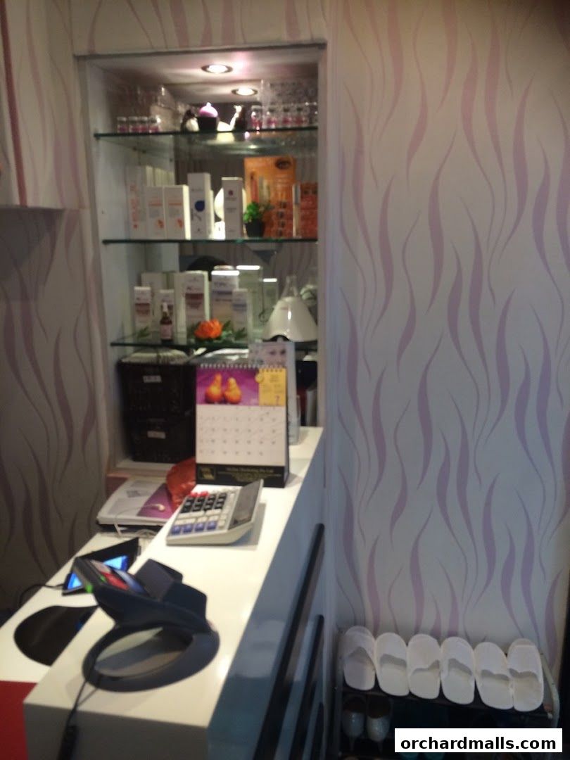 A reception desk with a calculator, phone, and display shelves with beauty products.