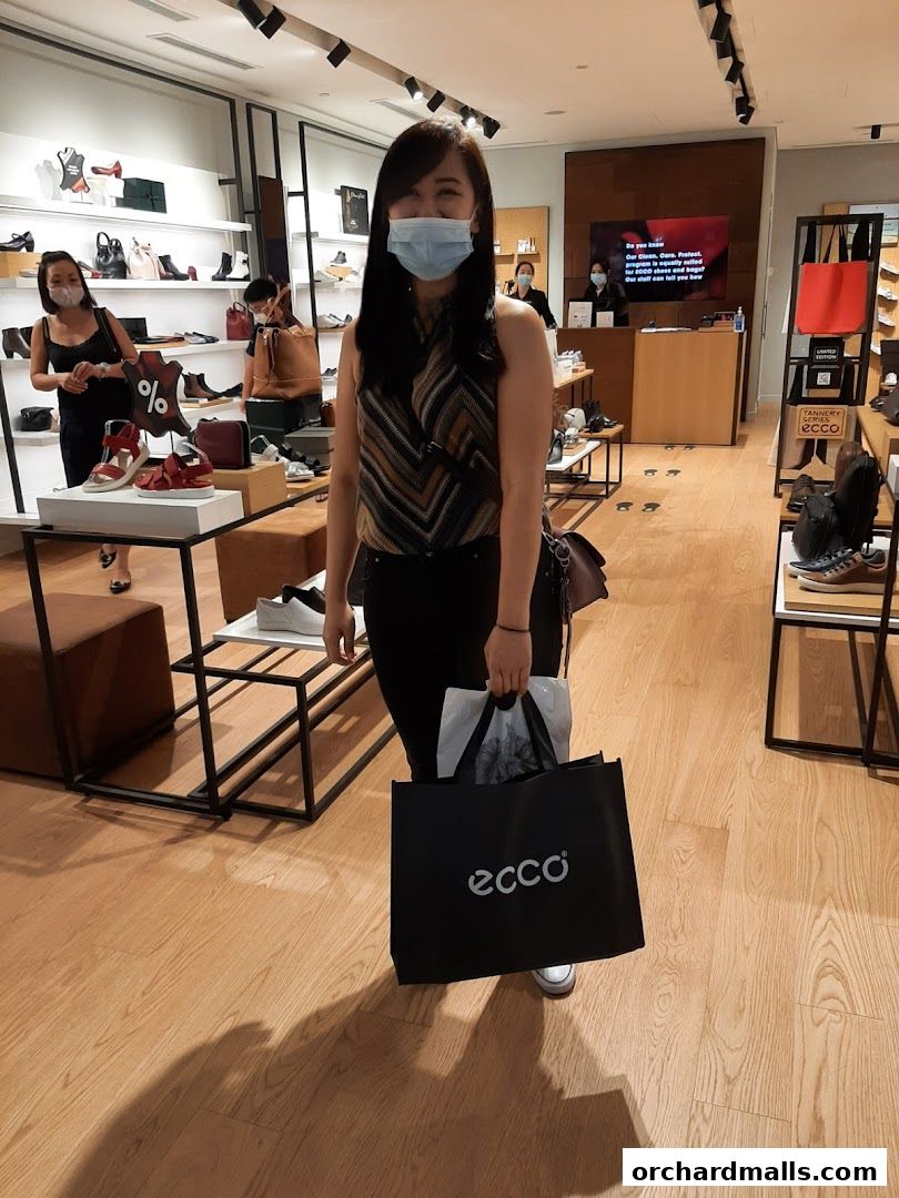 A woman with a shopping bag in an ECCO shoe store.